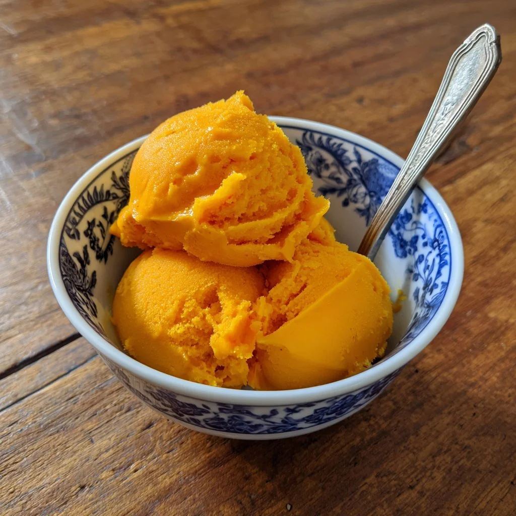 Mangosorbet mit Chili in einer Schale, kunstvoll garniert und serviert.
